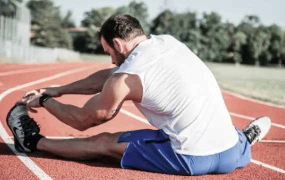 Sportler dehnt sich auf der Laufbahn bei chiropraktischer Betreuung in Braunschweig.